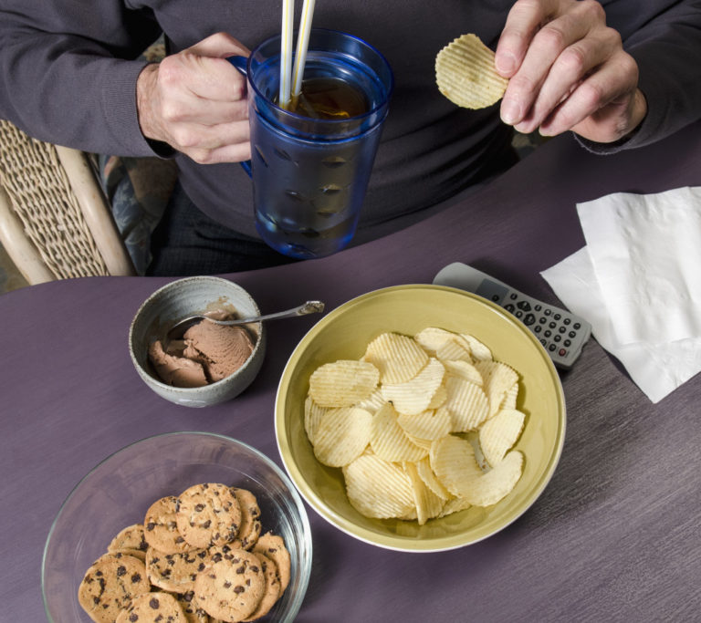 Man eating junk food watching television